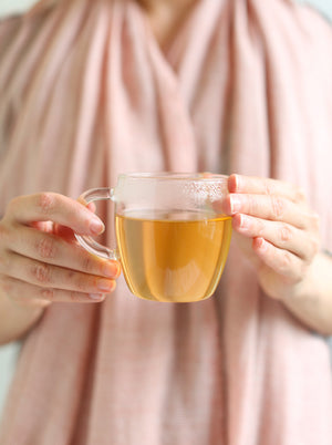 Lady holding glass mug of Dragonfly Tea